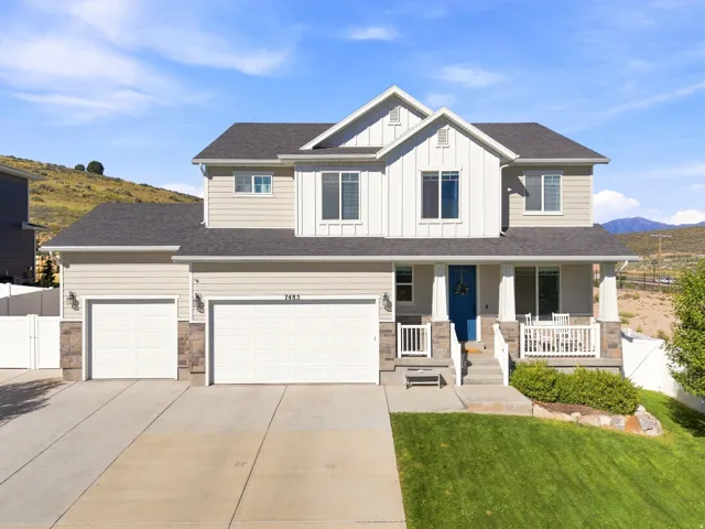 Two-story residence featuring a two-car garage, covered porch with white railings, and a blue entry door