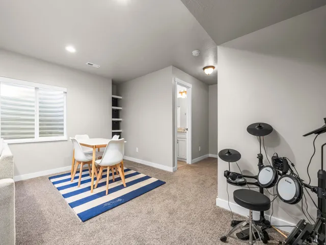 Recessed ceiling lighting, built-in shelving, carpet flooring, and a window with blinds