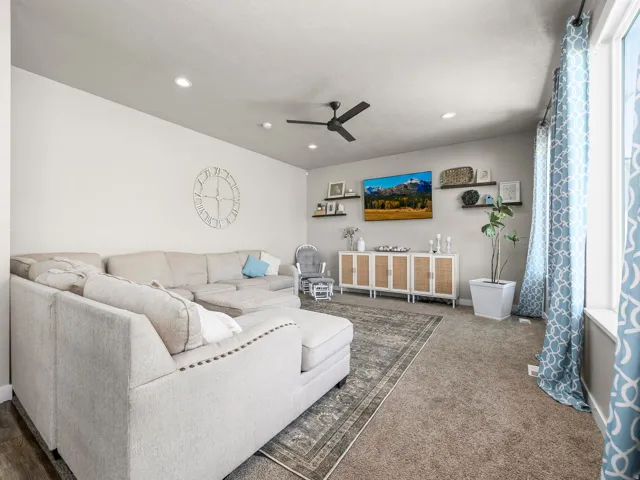 Spacious carpeted living area featuring recessed lighting, a ceiling fan, and floating wall shelves