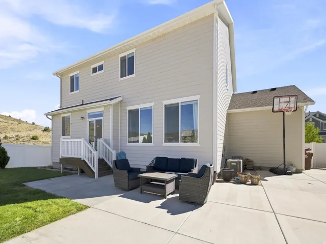 Rear exterior featuring light-colored siding, a white fenced perimeter, and a concrete patio