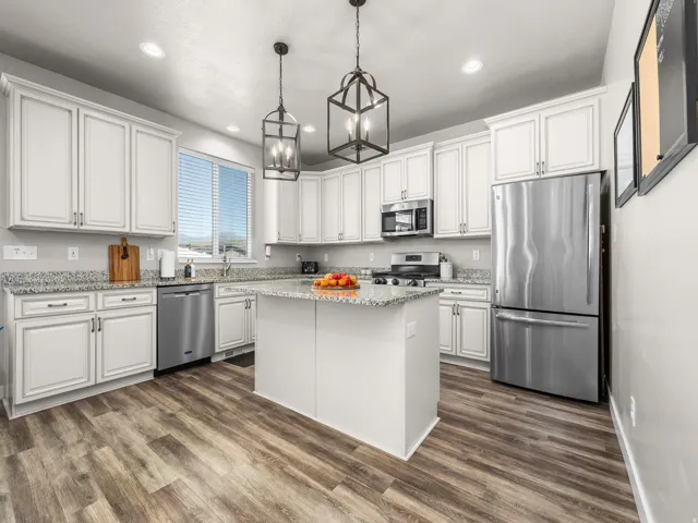 Kitchen featuring white cabinetry, stainless steel appliances, granite countertops, a center island, and wood-finish flooring