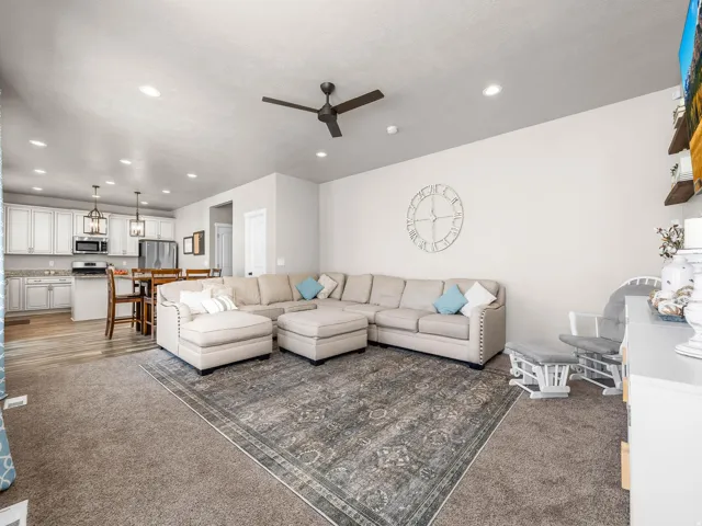 Open-concept living space featuring a ceiling fan, recessed lighting, and carpet flooring