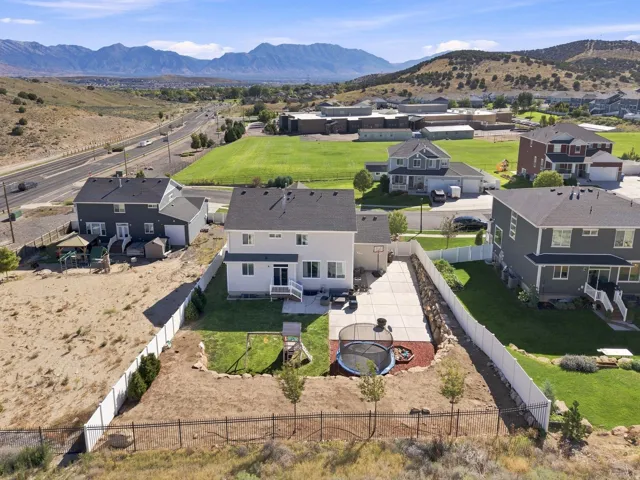 Rear exterior featuring a concrete patio, a fenced backyard with a lawn, and distant mountain scenery