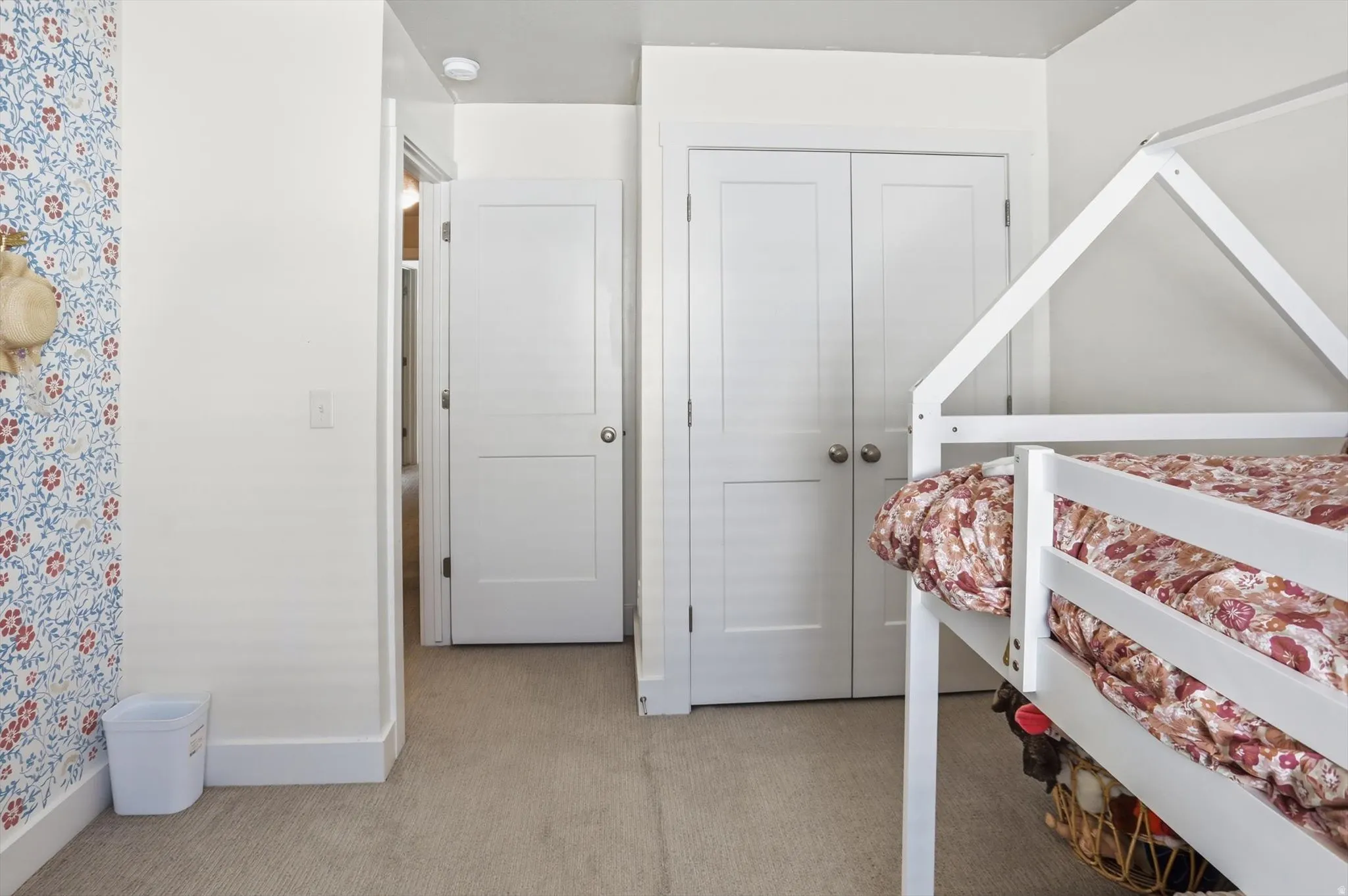 Wall-to-wall carpeting with white trim, a white paneled door, and bi-fold closet doors