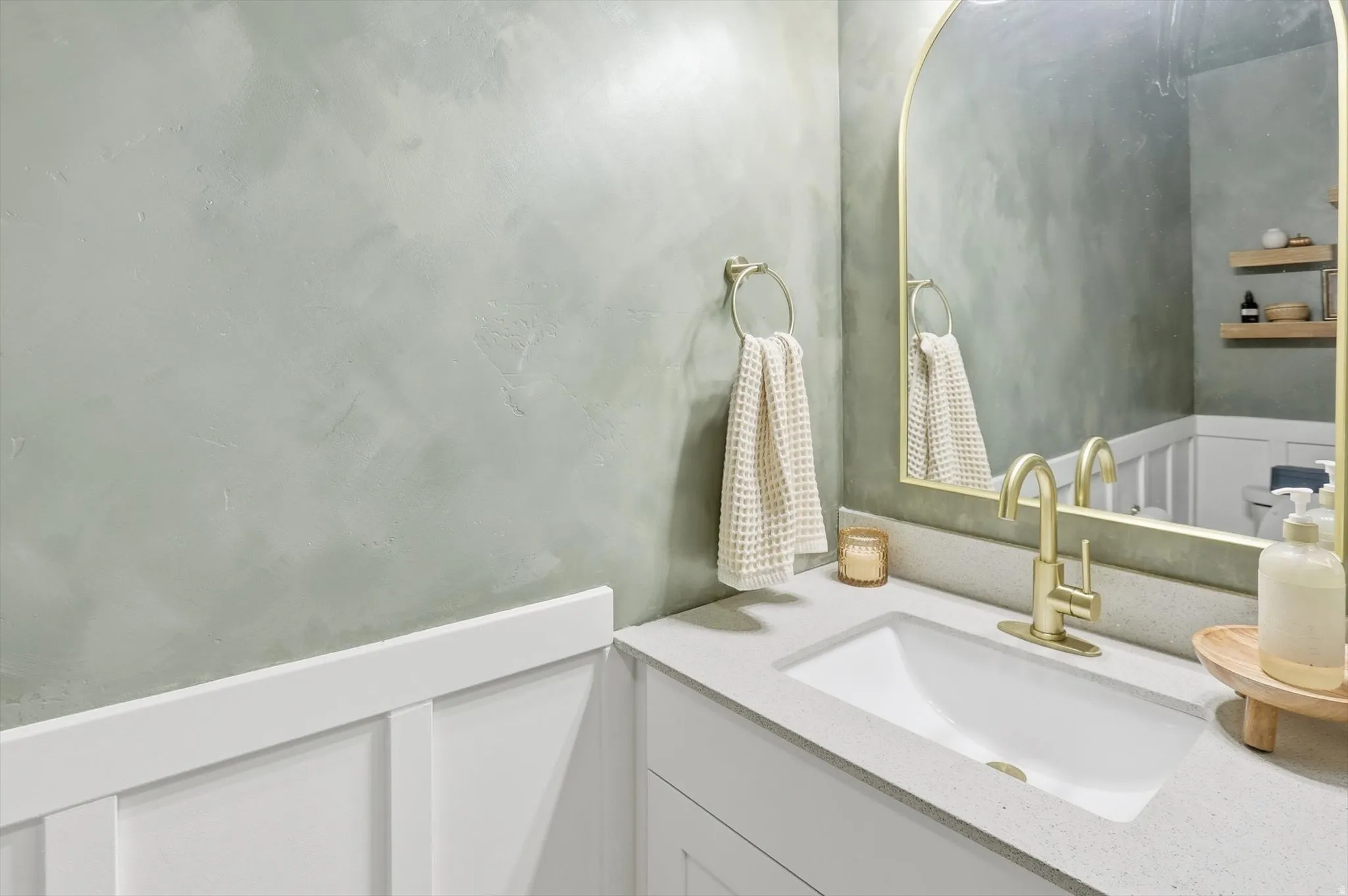 Integrated vanity with an undermount sink, brass-finish faucet, and coordinating arched mirror