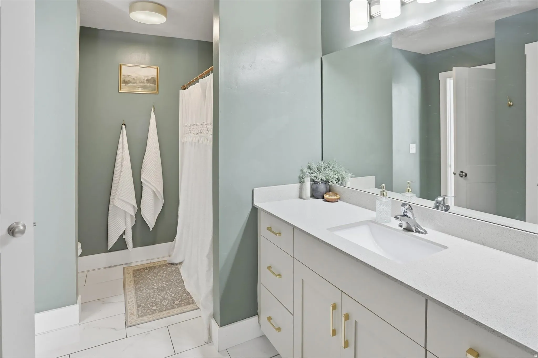 Vanity with a single integrated sink, light-colored countertop, and contemporary light fixture