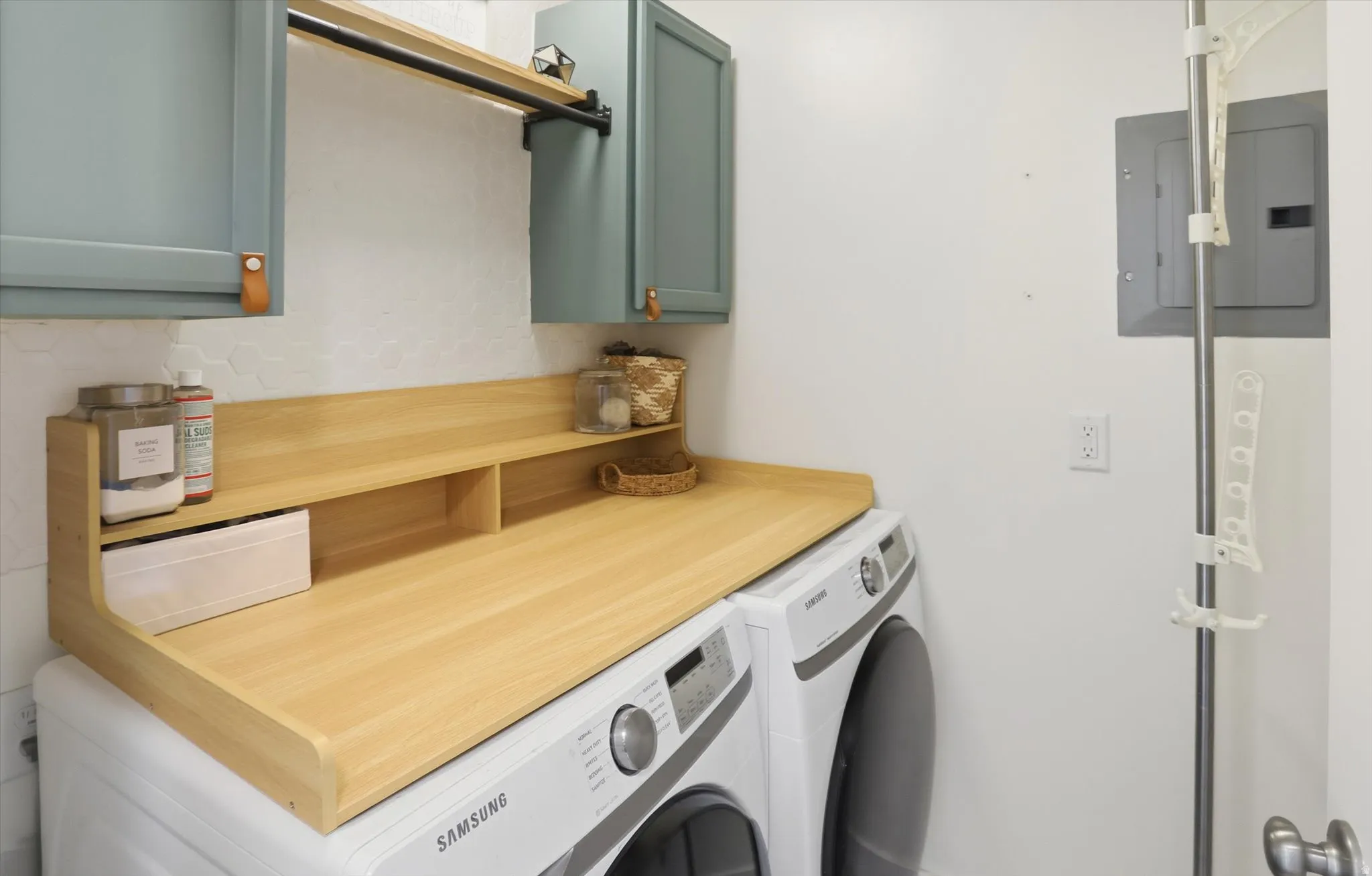 Wood-finish countertop with integrated shelving, two-tone cabinetry with leather pulls, and a mounted hanging rod