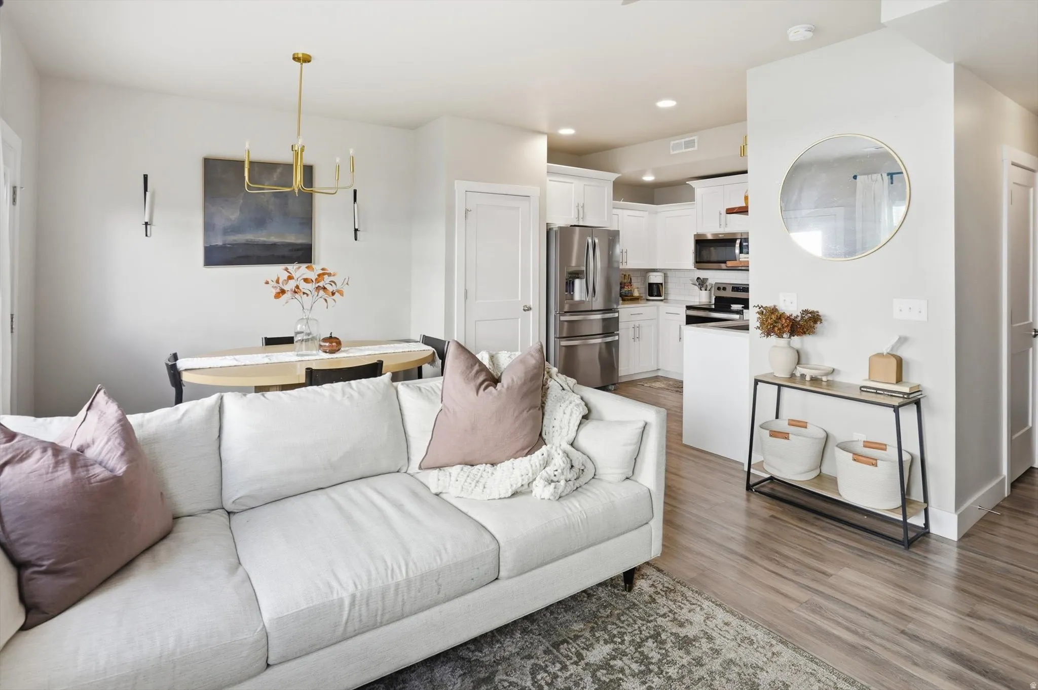 Open-concept living space featuring wood-finish flooring, recessed lighting, white cabinetry, and stainless steel appliances