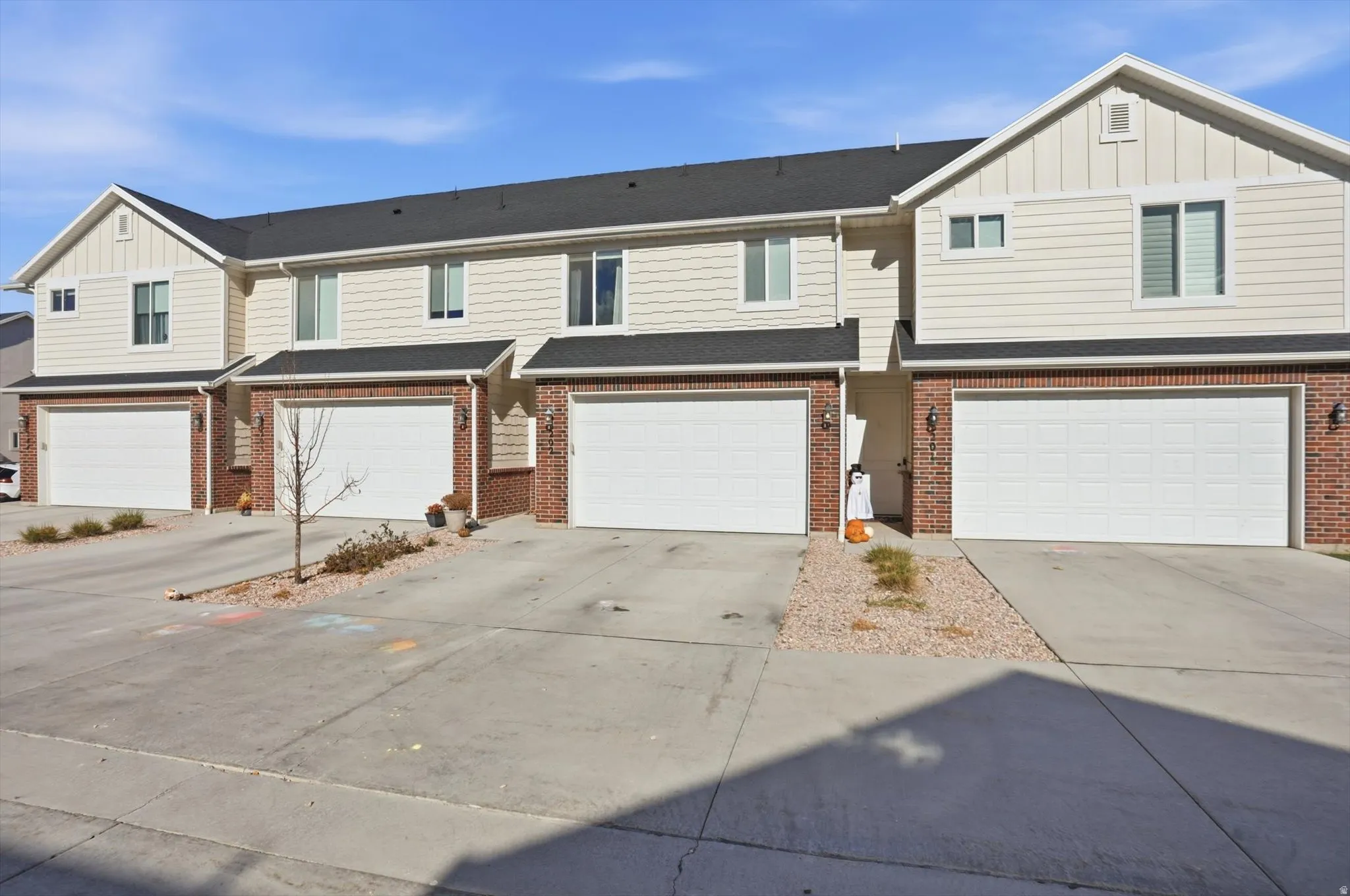Multi-unit exterior with brick and siding facade, individual garage doors, and concrete driveways