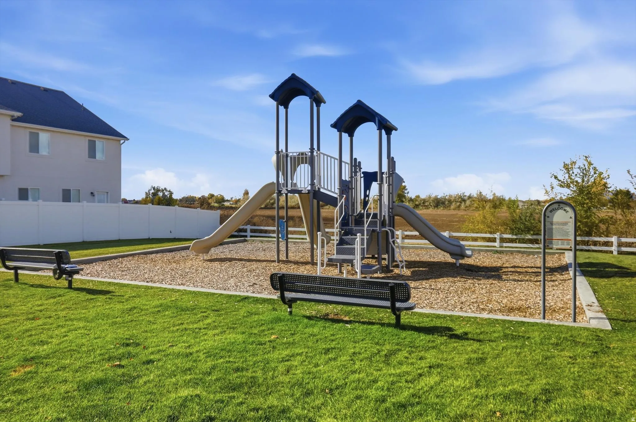 Community playground with two slides, benches, and wood chip surfacing