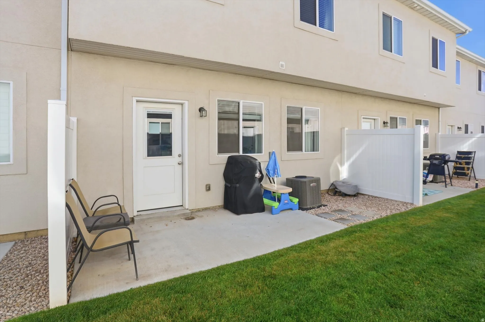 Private patio with concrete surfacing, adjacent to a manicured lawn area