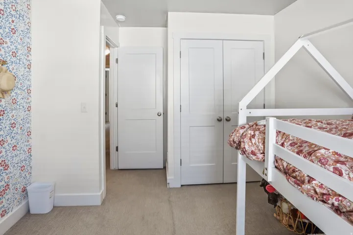Wall-to-wall carpeting with white trim, a white paneled door, and bi-fold closet doors