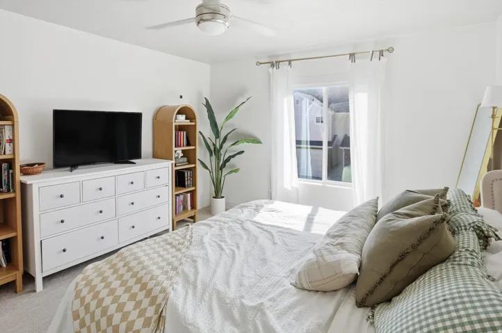 White walls and ceiling, ceiling fan with light fixture, window with drapes, and carpeted flooring