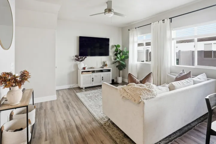Wood-finish flooring, recessed lighting, ceiling fan, white window treatments, and a built-in media console