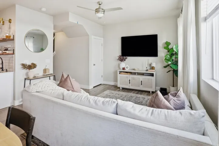 Open-concept living area featuring wood-finish flooring, a contemporary ceiling fan, and a media console
