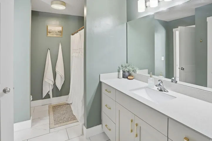 Vanity with a single integrated sink, light-colored countertop, and contemporary light fixture