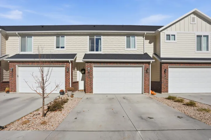 Townhome exterior featuring brick and horizontal siding, individual garage access, and concrete driveways