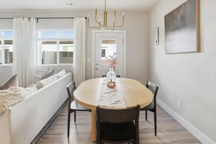 Open-concept living area featuring light-toned wood-finish flooring, multiple windows, and a glass-paneled door
