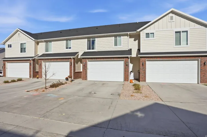 Multi-unit exterior with brick and siding facade, individual garage doors, and concrete driveways