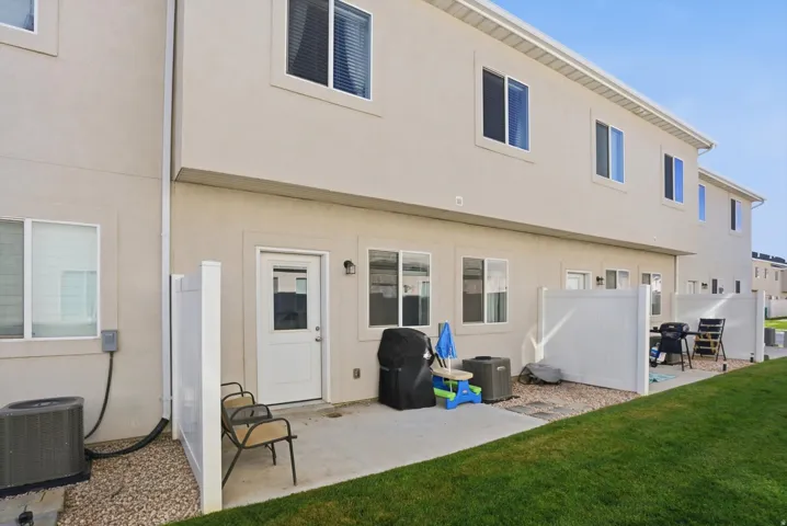 Rear patio with concrete slab, white privacy fencing, and adjacent grassy area