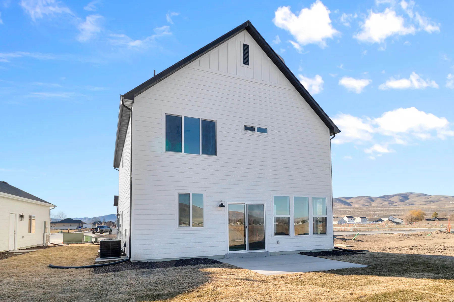 Modern farmhouse exterior with white siding, black trim, and a prominent gable