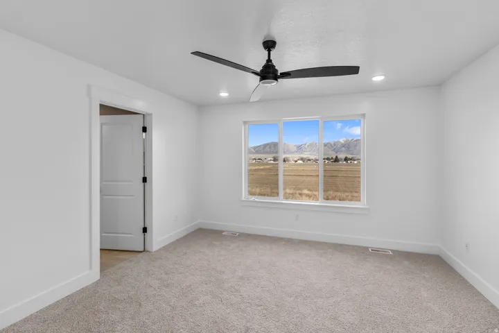 Expansive room featuring a large window, mountain scenery, overhead lighting, and a ceiling fan