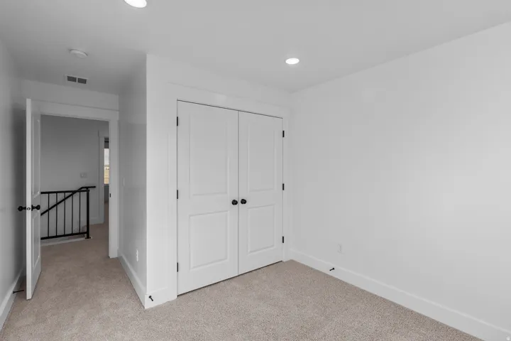 Recessed ceiling lighting, white bi-fold closet doors, wall-to-wall carpeting, and white trim