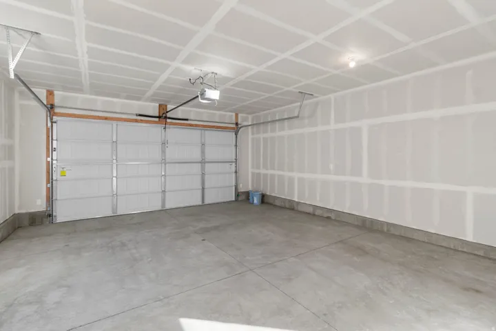 Spacious garage with a concrete floor, overhead lighting, and an automatic garage door opener