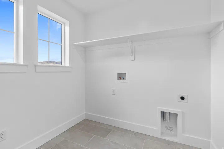 Utility room featuring dual windows, a built-in shelf, and tile flooring