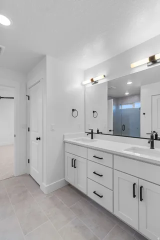 Dual vanity with white shaker-style cabinetry, matte black hardware, and integrated sinks with black faucets