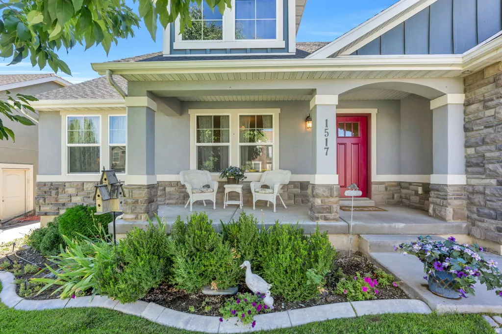 Covered front porch with substantial columns, stone facade accents, and a vibrant red entry door