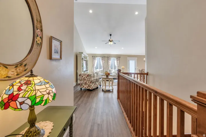 Vaulted ceiling with recessed lighting, wood-finish flooring, and natural wood railing