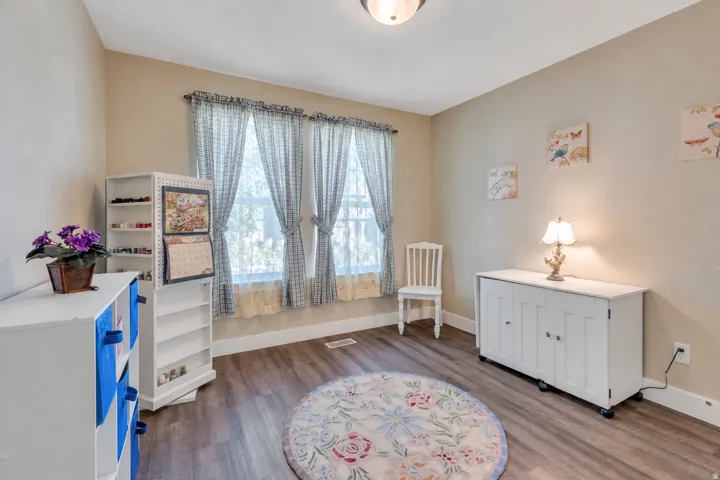 Wood-finish flooring, two windows with decorative valances, and a ceiling-mounted light fixture