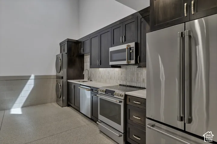 Compact kitchen featuring dark wood cabinetry, stainless steel appliances, a tiled backsplash, and light-toned countertops
