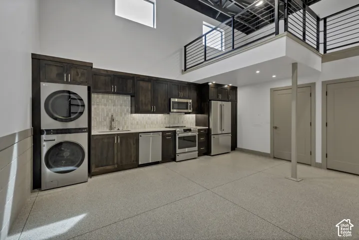 Integrated full kitchen with stainless steel appliances, dark wood-finish cabinetry, and white subway tile backsplash