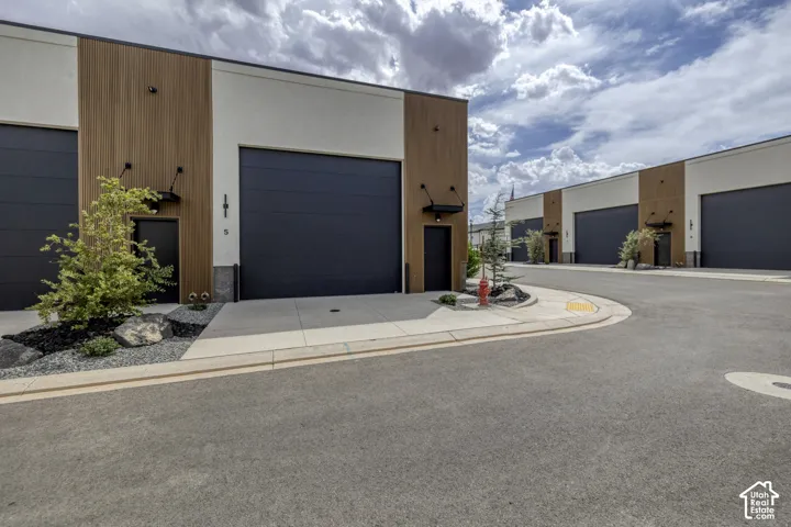 Contemporary exterior with wood-finish paneling and dark gray overhead doors
