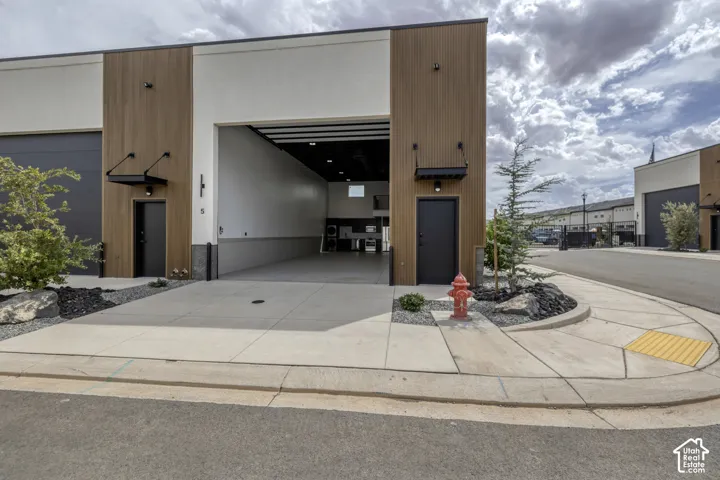 Modern commercial building with a roll-up garage door, pedestrian entryways, and exterior lighting