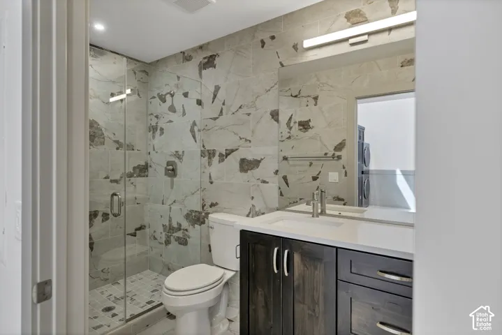 Walk-in shower with clear glass enclosure and tile surround, vanity with dark wood-finish cabinetry, white countertop, and large wall mirror
