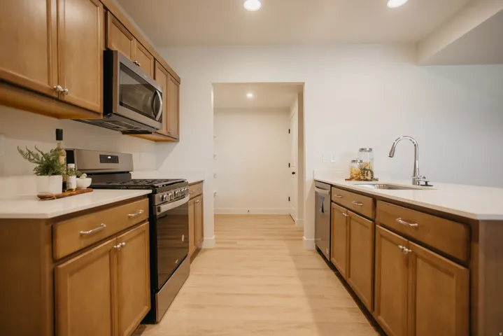 Kitchen featuring wood-finish cabinetry, stainless steel appliances, light-toned countertops, and light-toned flooring