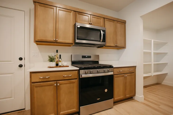 Kitchen featuring stainless steel appliances, light wood-finish cabinetry, and solid surface countertops