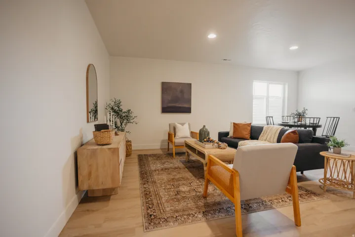 Spacious open-concept room featuring light-toned walls, recessed lighting, and wood-finish flooring