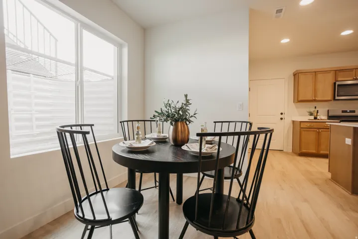 Light wood-finish flooring, kitchen with wood cabinetry and stainless steel appliances, recessed ceiling lighting, and a large window