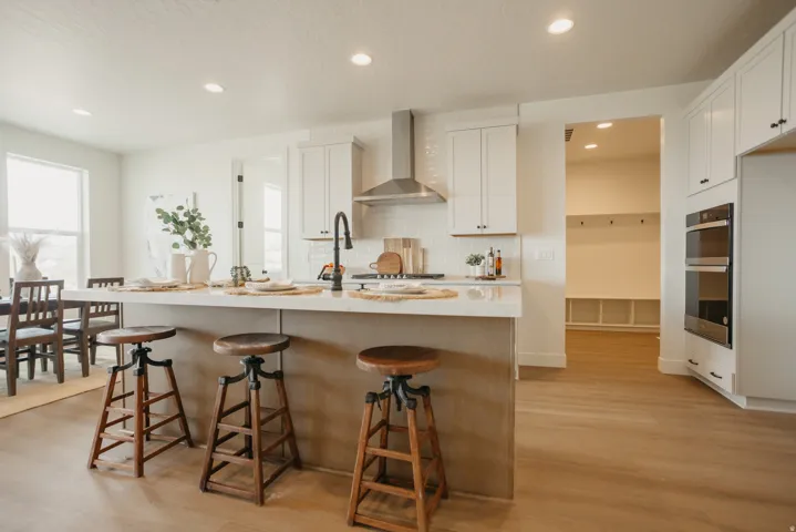 Kitchen featuring a large island with counter seating, stainless steel appliances, white cabinetry, and wood-finish flooring