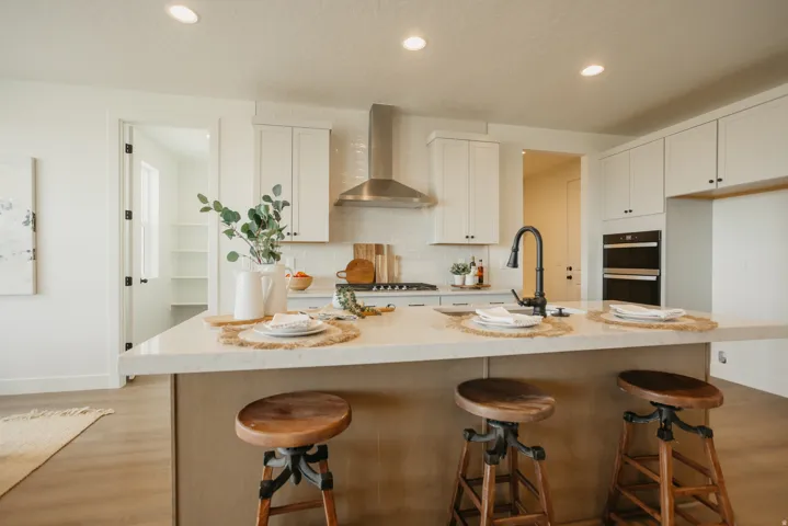 Kitchen featuring an eat-in island with countertop seating, stainless steel appliances, white cabinetry, wood-finish flooring, and a walk-in pantry