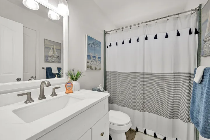 White vanity with integrated sink, brushed nickel faucet, large vanity mirror, and overhead vanity lighting