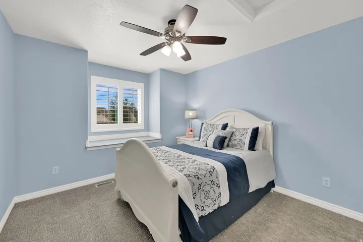 Recessed ceiling with an integrated ceiling fan, light blue walls, window with white shutters, and gray carpeting