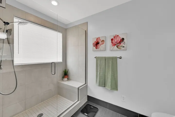 Glass-enclosed shower with a built-in bench, tiled walls, and a recessed light fixture