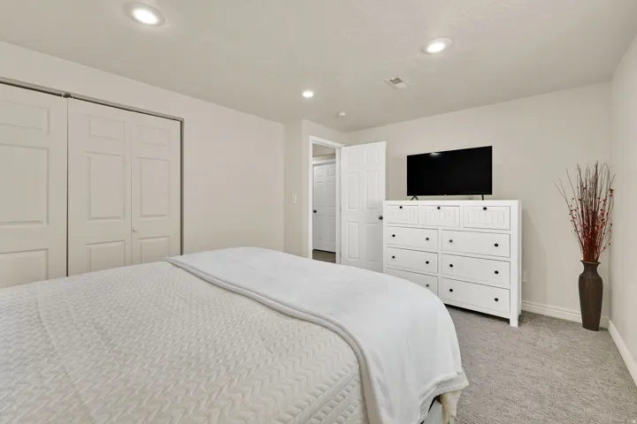Plush carpet flooring, recessed ceiling lighting, and bi-fold closet doors