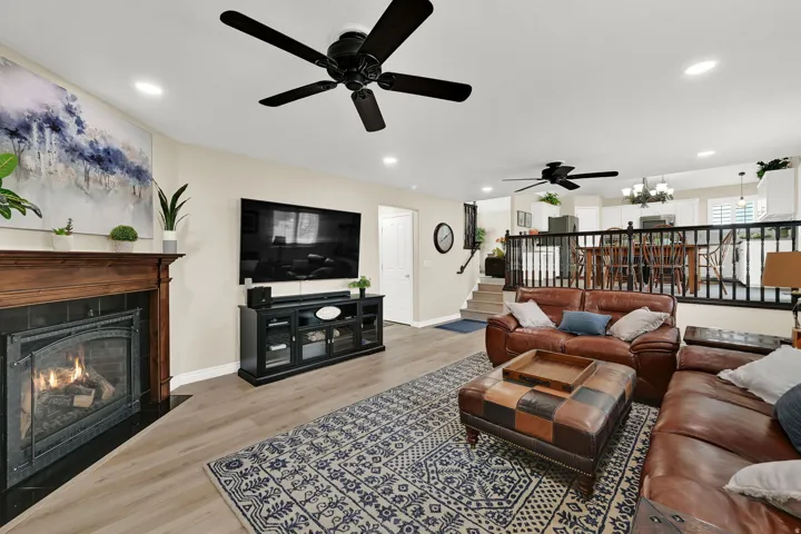 Warm living space featuring wood-finish flooring, a fireplace with a dark tile surround and wood mantel, and recessed lighting