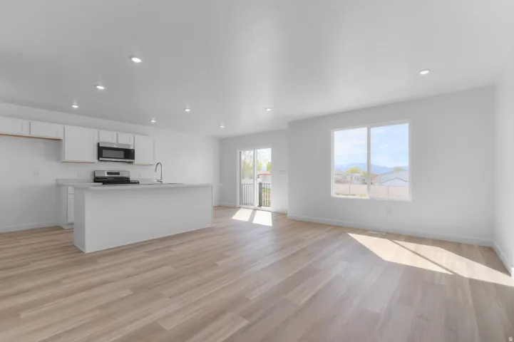 Open-concept living space featuring wood-finish flooring, recessed lighting, and white walls